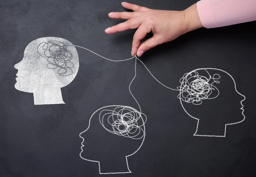 Dibujo en pizarra de tres siluetas de cabezas conectadas por hilos. Representación visual de psicólogo en inglés y la interconexión.